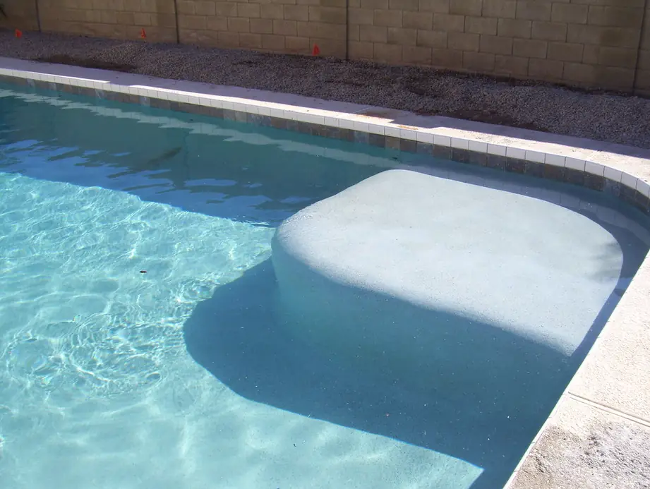 Clear water over a white plaster bench step along a block wall